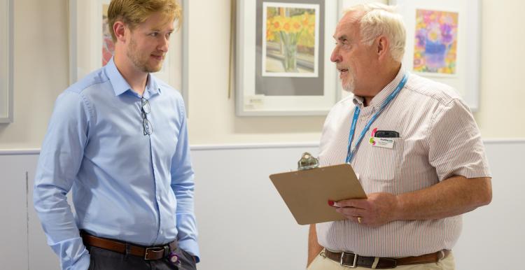 Two men stood chatting over a clipboard