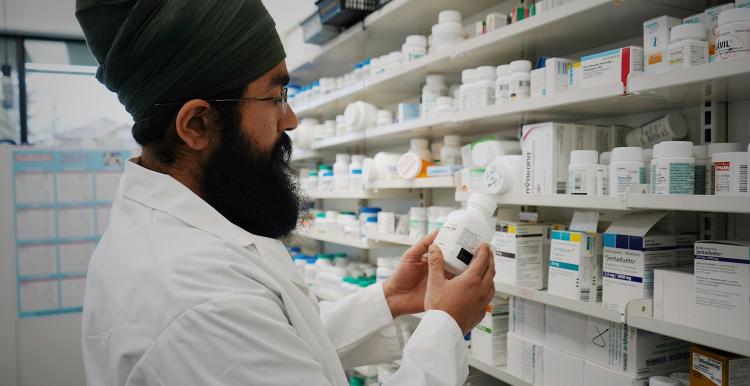 Man selecting medicine from shelves in a pharmacy