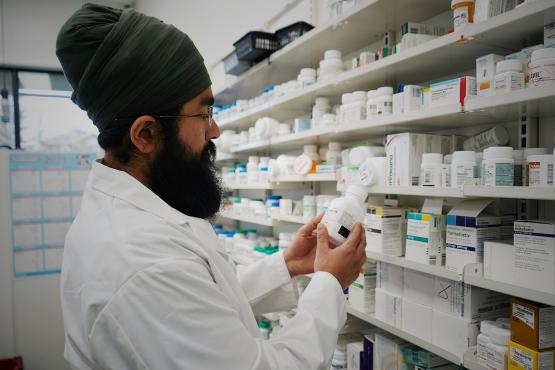 Man selecting medicine from shelves in a pharmacy