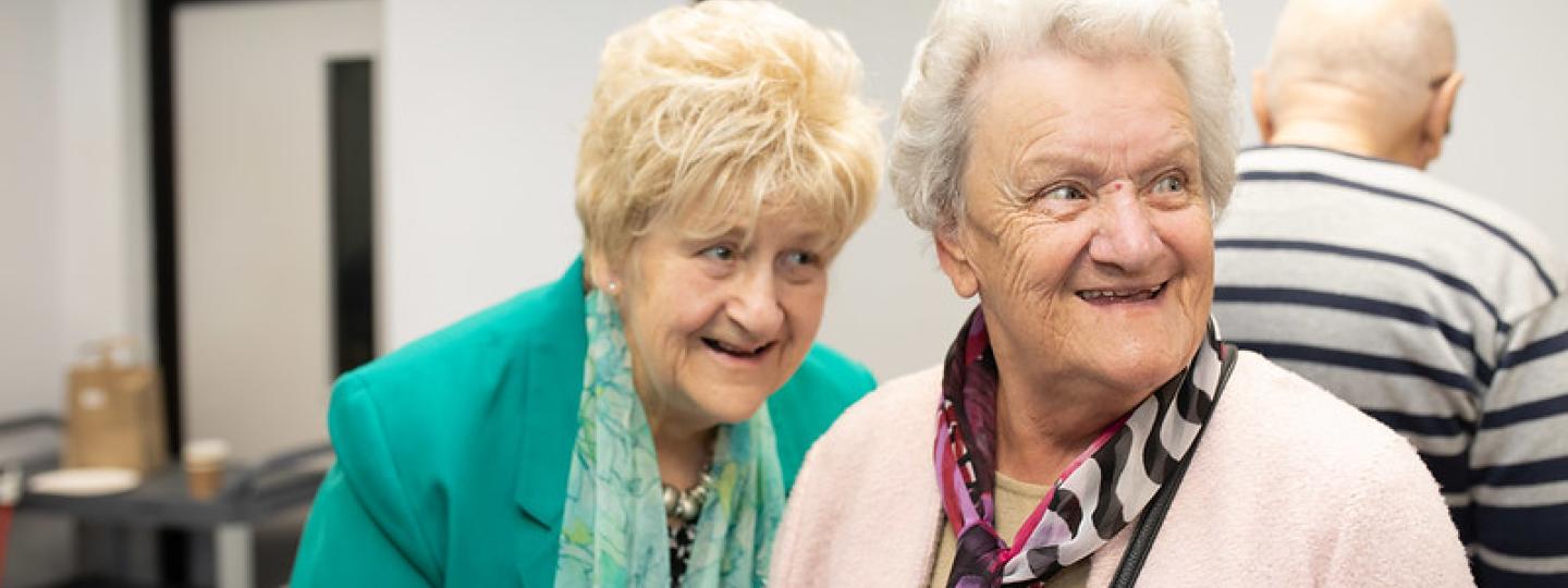 Two elderly women having a giggle together